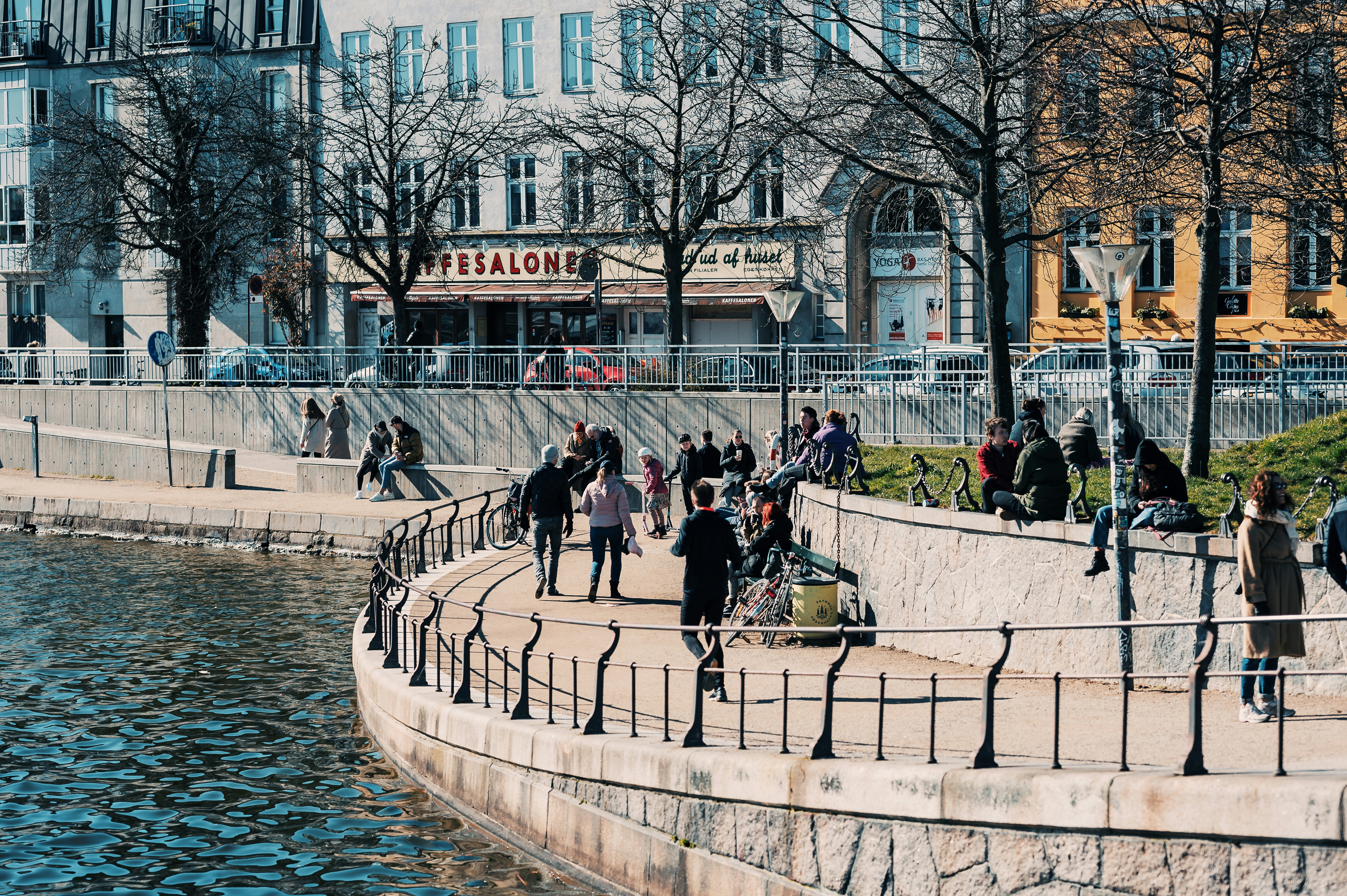 People enjoying the harbor area in Copenhagen with boats and warm sunlight
